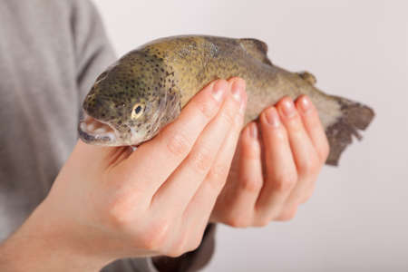 A young man has a fish in his handの写真素材