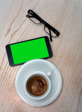 Top view of glasses, smartphone and coffee on wooden desk.のeditorial素材