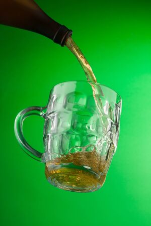 Pouring ice cold Beer from bottle into glass, view from bottomの写真素材