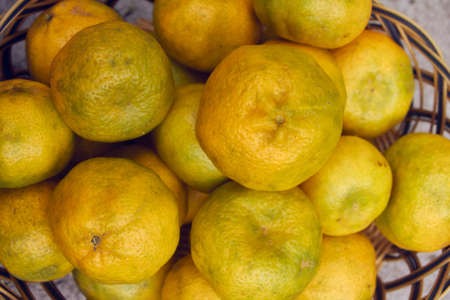 yellow ripe tangerines in a basket, green tones, big fruit