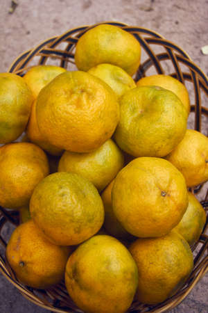 yellow ripe tangerines in a basket, green tones, big fruitの写真素材