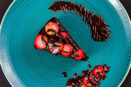 chocolate cake with strawberries in turquoise dish, closeup