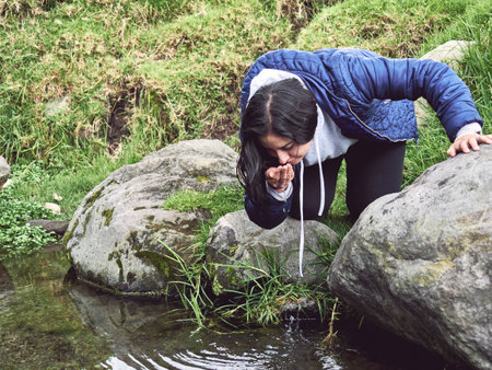 Embracing the Wild: Woman Hiking and Splashing Through a Riverの写真素材