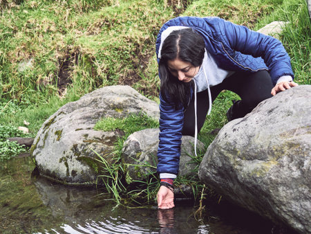 Embracing the Wild: Woman Hiking and Splashing Through a Riverの写真素材
