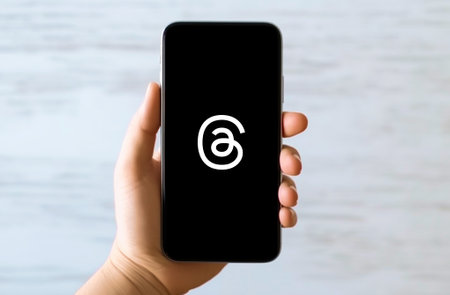 Hand holding phone with threads social media logo icon, smartphone interfaceのeditorial素材