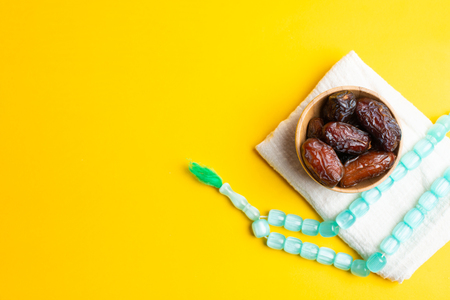 Ramadan Kareem Festival, Dates at bowl with rosary on yellow backgroundの写真素材