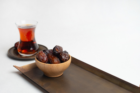 Ramadan Kareem Festival, Dates at wooden bowl with cup of black tea on white backgroundの写真素材