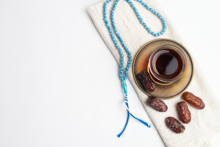 Ramadan Kareem Festival, Dates on wooden bowl with cup of black tea and rosary on white isolated backgroundの写真素材