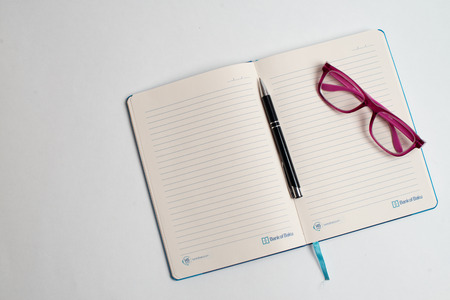 Close up Glasses and pen on notebook on tableの写真素材