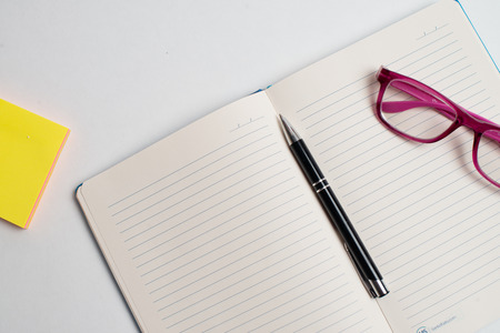 Close up Glasses and pen on notebook on tableの写真素材