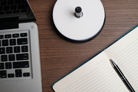 Notebook with black pen, Colorful notepads on the desk, Glasses on the desk with pen and cup of coffee, Computer keyboard with colorful note stickの写真素材
