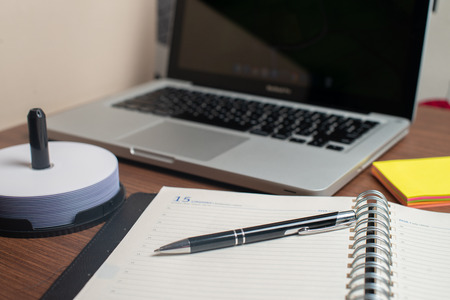 Notebook with black pen, Colorful notepads on the desk, Glasses on the desk with pen and cup of coffee, Computer keyboard with colorful note stickの写真素材