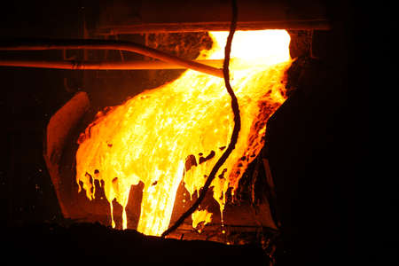 Hot steel pouring in steel plant. Molten metal poured from ladle. Metallurgical production, heavy...