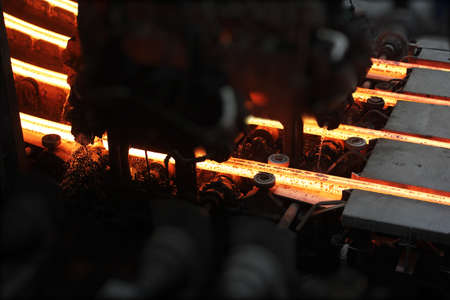 Red hot steel metal billets after molten steel casting.  Continuous casting machine. Background of...