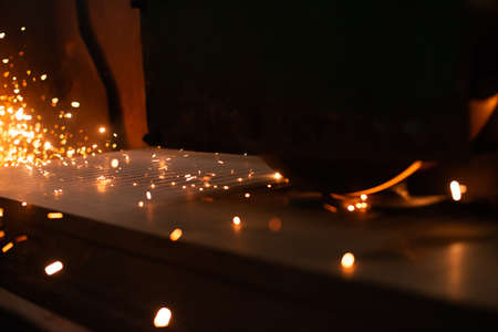 Sheet metal plate with sparking light. CNC Laser cutting of metal, modern industrial technology. Manufacturing finished parts.の写真素材