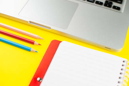 Laptop, colorful pencils and notepad planner on yellow background. Flat lay. Copy space. Workplace...