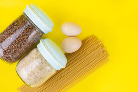 Food stock for quarantine isolation period on yellow background. Rice, egg, buckwheat, spaghetti. Food delivery, Donation. Copyspaceの写真素材