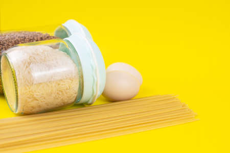 Food stock for quarantine isolation period on yellow background. Rice, egg, buckwheat, spaghetti....