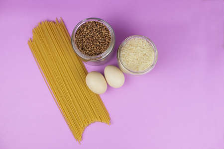 Food stock for quarantine isolation period on purple background. Rice, egg, buckwheat, spaghetti. Food delivery, Donation. Copyspaceの写真素材