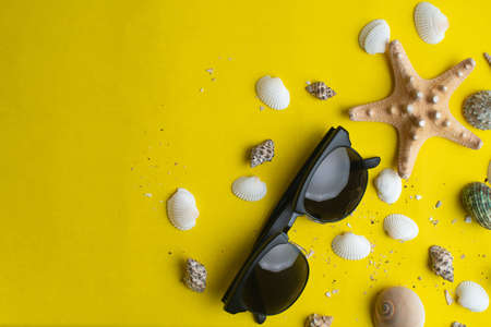 Summer accessories, shells and sun glasses on yellow background. Summer vacation. Sea concept.の写真素材