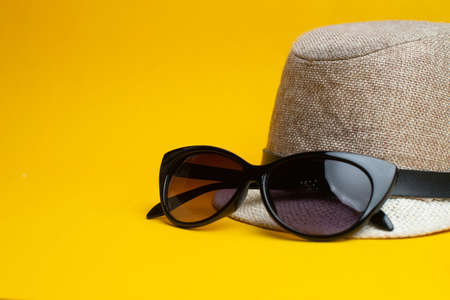 Summer accessories, hat and sun glasses on yellow background. Summer vacation and sea concept. Copyspace for text.の写真素材