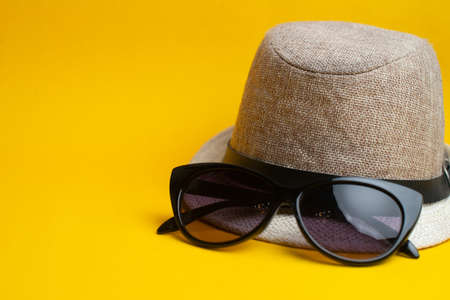 Summer accessories, hat and sun glasses on yellow background. Summer vacation and sea concept. Copyspace for text.の写真素材