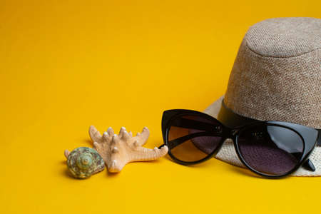 Summer accessories, shells, hat and sun glasses on yellow background. Summer vacation.の写真素材