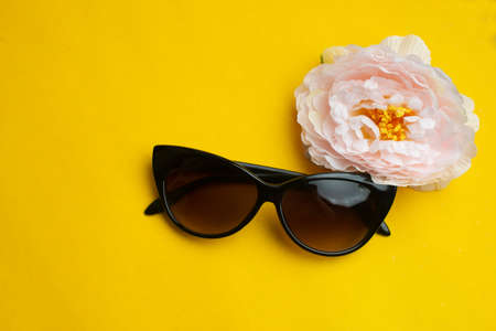 Woman sunglasses with flower on yellow background. Summer vacation concept.の写真素材