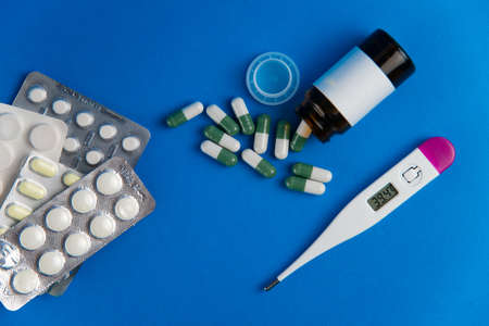 Coronavirus 2019-nCoV outbreak. Pills and drug, care during illness. Thermometer and drugs on blue...