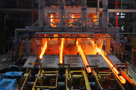 Red hot steel metal billets after molten steel casting.  Continuous casting machine. Background of...