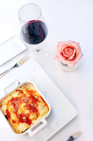 Baked pasta lasagna and red wine at lunch with table ornamentの写真素材