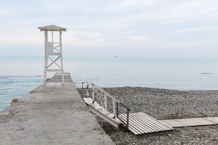 White wooden rescue tower on the breakwater. Low staircase lead down from the seawall to the beachの写真素材