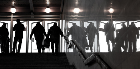 Human silhouettes against the bright doors. Exit from underground. People shadows with reflection on...