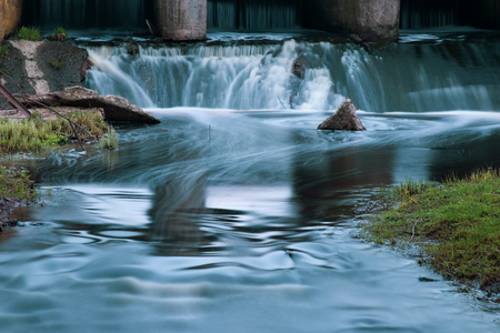 Part of the concrete structure of the river dam. Water blurred by long exposureの写真素材