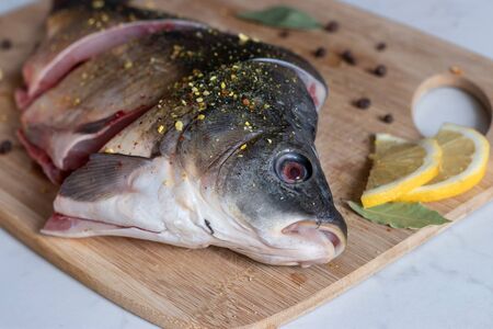 Close up of  sliced raw carp with peppers and lemon on cutting board. Cooking fish. Focus on...