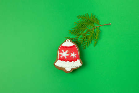 Creative Christmas concept with gingerbread bell and spruce branch on green background. Happy New Year. Minimal flat layの写真素材