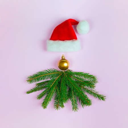 Santa Claus face made of fir branches, Christmas golden bauble and Santa hat. Creative concept of Christmas and New Year. Layout, top viewの写真素材