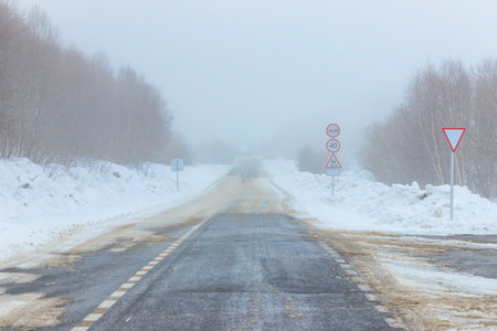 Empty snow covered road. Road signs, fog. Winter landscapeの写真素材