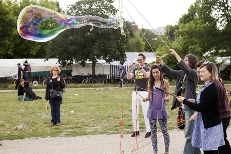 Berlin, Germany - June 1oth, 2012: Agroup of young adults are making giant soap bubbles on an early summer Sunday afternoon at Mauerpark, with the flea market in the background.のeditorial素材