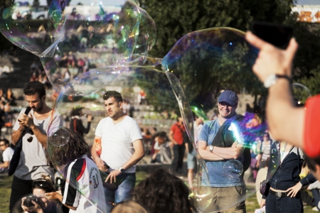 Berlin, Germany - June 10th, 2012: The crowd at Mauerpark seen through giant soap bubbles on an...