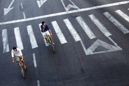 Tel-Aviv, Israel - October 8th, 2011: High angle view of two adult men riding on bicycles at the empty Maariv intersection in Tel-Aviv. They have the privilege of riding securely in the middle of the street because it is the Day of Atonement (Yom-Kippur),のeditorial素材