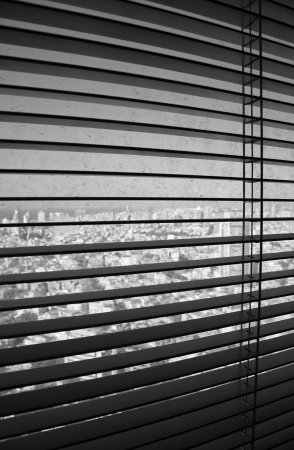Venetian blinds in their open position, revealing a dirty window with defocused Tel-Aviv buildings...