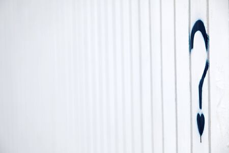 A blue grafitti in the shape of a question mark with a small heart instead of the dot, on a white metal wall with creases pattern.の写真素材
