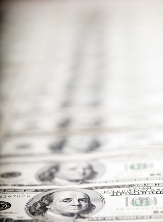 A large quantity of 100 US$ money notes lined up in a vertical row. Very shallow depth of field.の写真素材