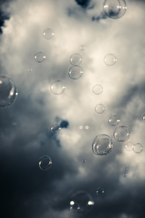 Soap sud bubbles floating in the air on the background of dramatic sky with heavy gray clouds の写真素材