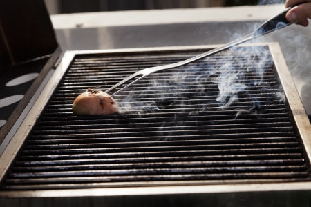 Getting the grill ready for some cooking - rubbing halved onion on the hot grate.の写真素材