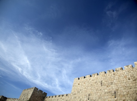 The surrounding wall of the old city of Jerusalem beneath a spectacular cloudy blue sky の写真素材