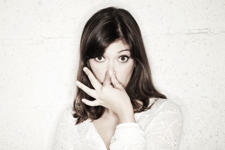 Portrait of a beautiful young woman staring into the camera with her eyes wide open and covering her nose with two fingers. Apparently something stinks.の写真素材