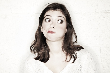 Portrait of a beautiful young woman with her eyes wide open, glancing sideways, she's looking completely shocked in the cutest manner possible.の写真素材