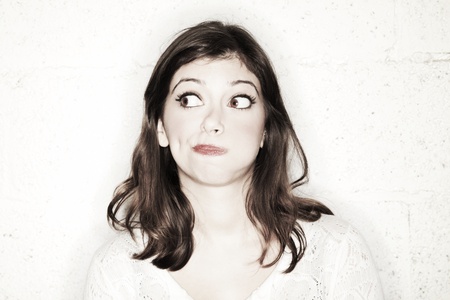 Portrait of a beautiful young woman with her eyes wide open, glancing sideways, she's looking completely clueless in the cutest manner possible.の写真素材